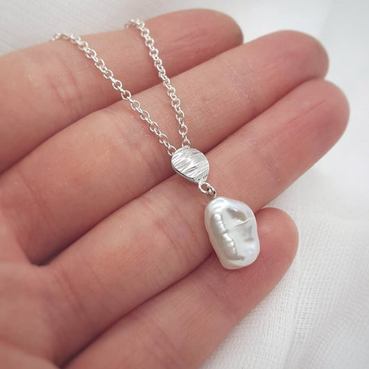 white keshi pearl necklace with silver textured detail on a trace chain