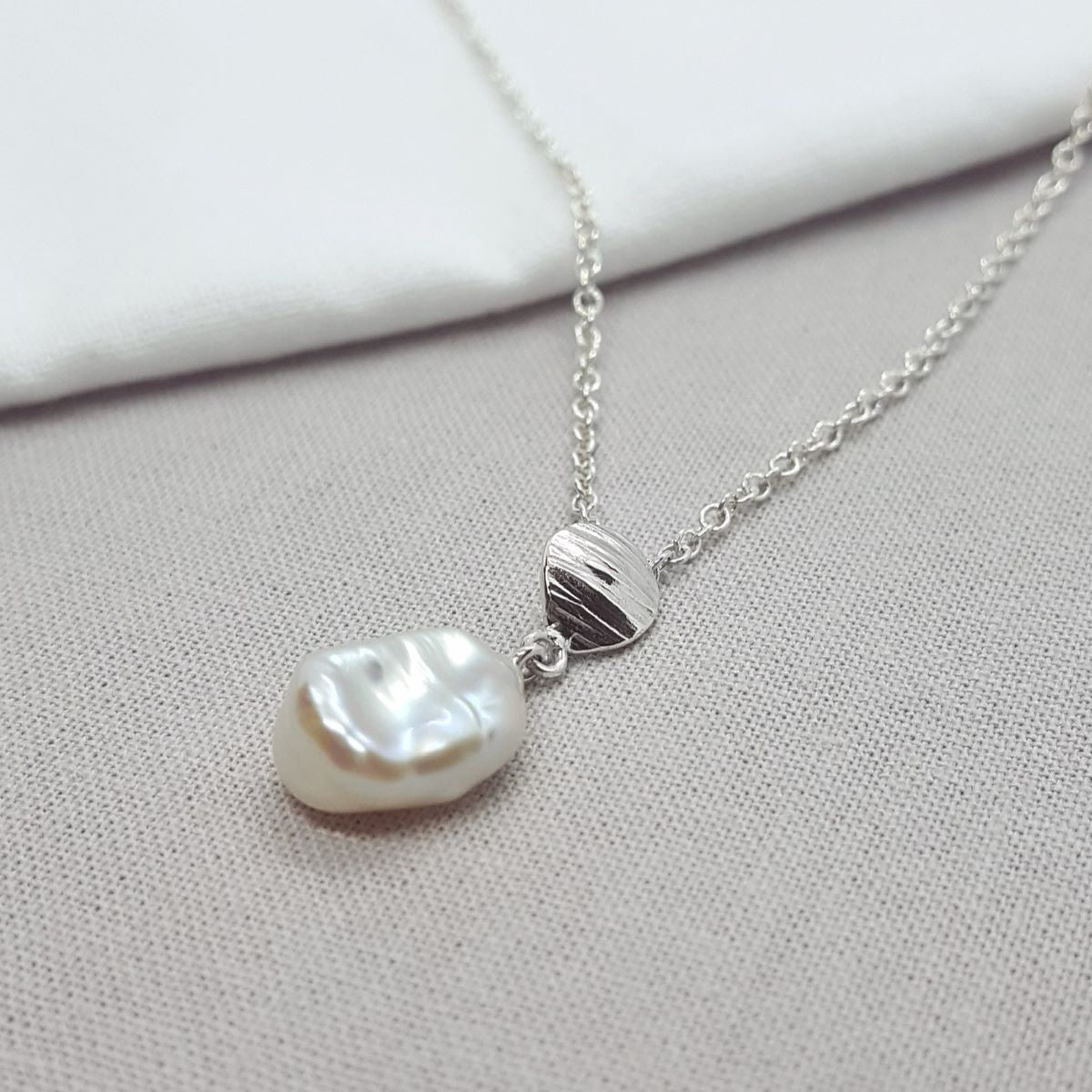 white keshi pearl necklace with silver texture detail, hanging on a silver trace chain, handmade jewellery in Kent