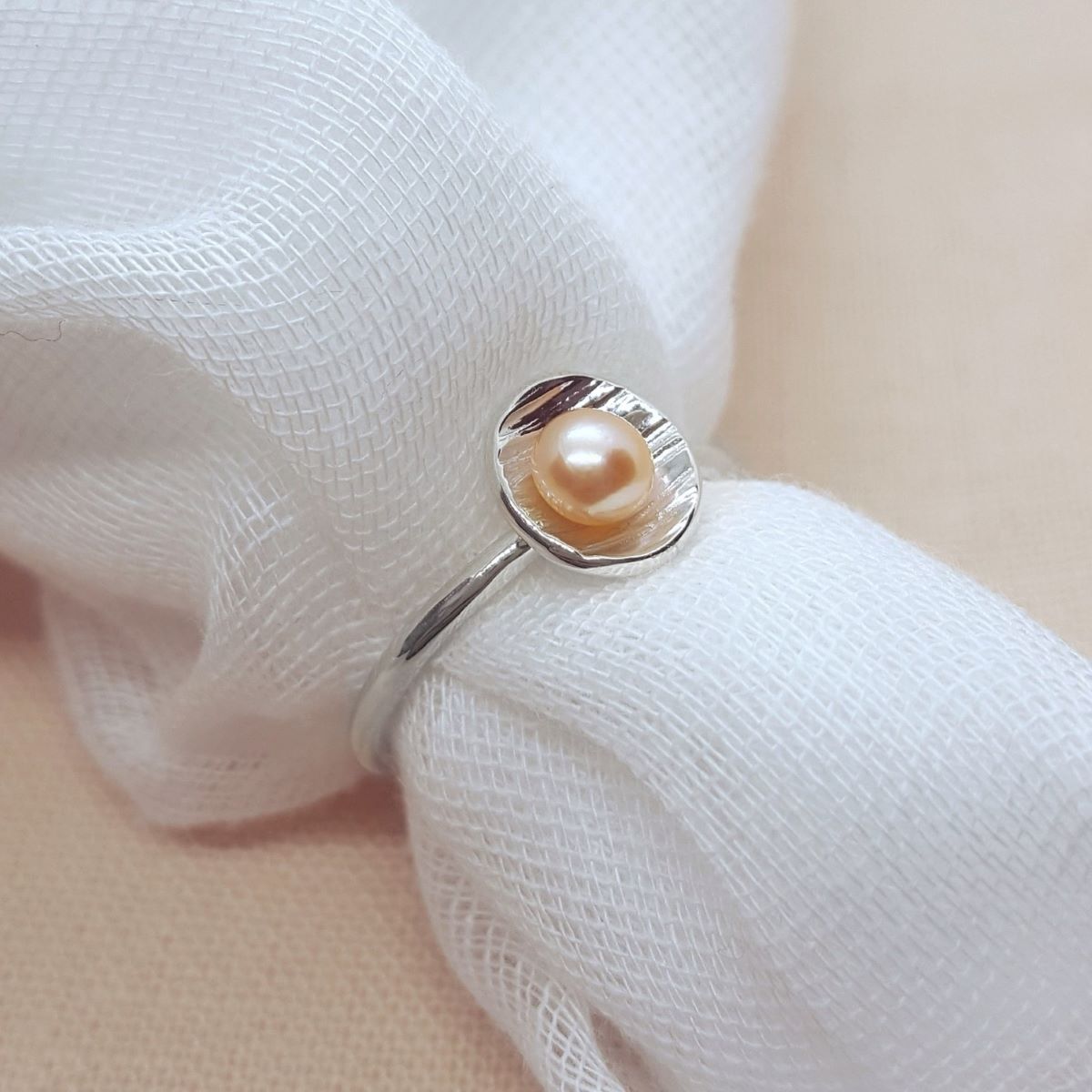 peach button freshwater pearl set in a textured silver cup ring