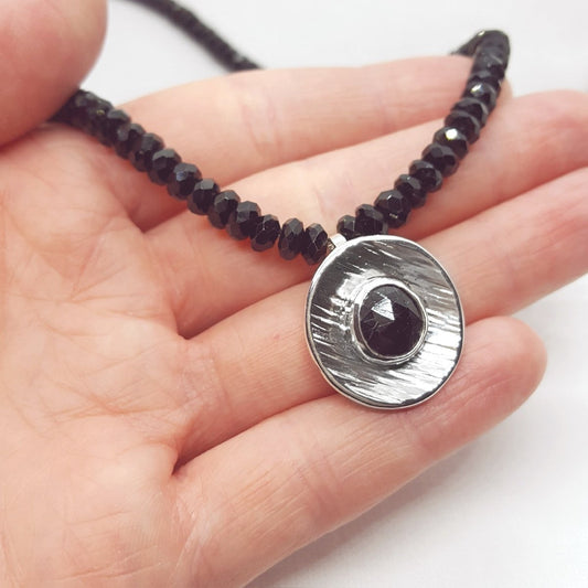 rose cut black tourmaline, set in a large textured silver disc and hung from a strand of black tourmaline faceted beads. Handmade in Kent