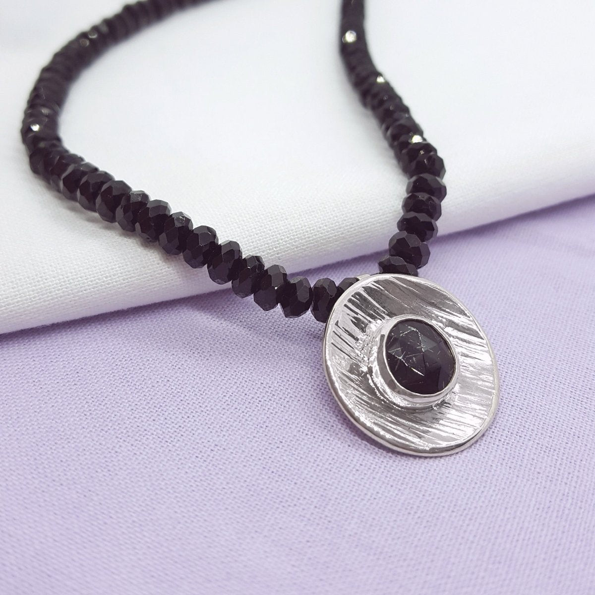 rose cut black tourmaline, set in a large textured silver disc and hung from a strand of black tourmaline faceted beads. Handmade in Kent