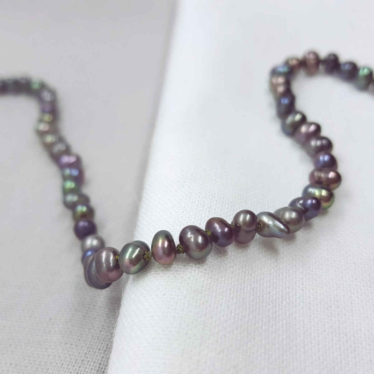 peacock potato freshwater pearl necklace hand knotted on olive coloured silk thread and finished with a handmade silver clasp.