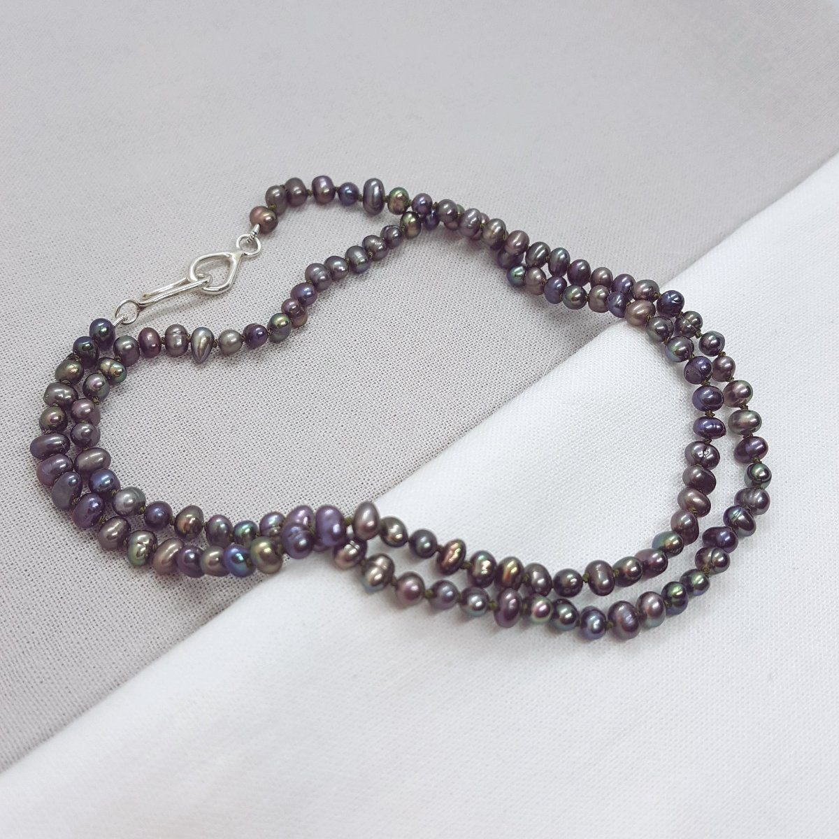 peacock potato freshwater pearl necklace hand knotted on olive coloured silk thread and finished with a handmade silver clasp.
