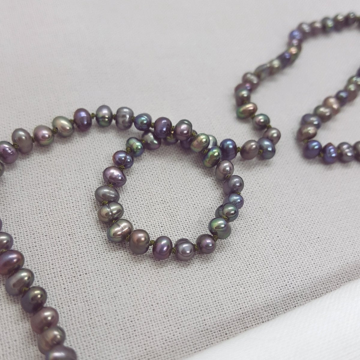 peacock potato freshwater pearl necklace hand knotted on olive coloured silk thread and finished with a handmade silver clasp.
