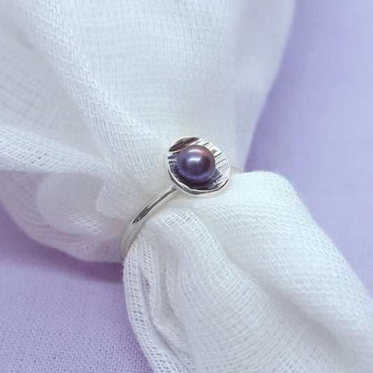 peacock coloured freshwater pearl set in a silver textured cup, silver wire band, handmade jewellery in Kent