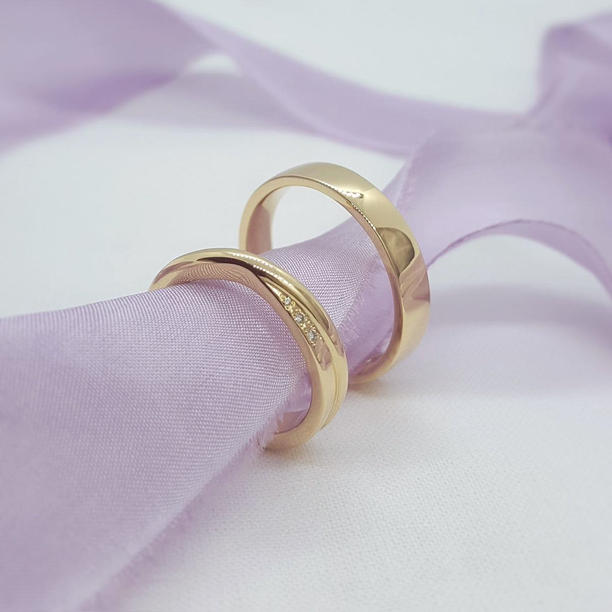 Two gold rings on a soft purple fabric background