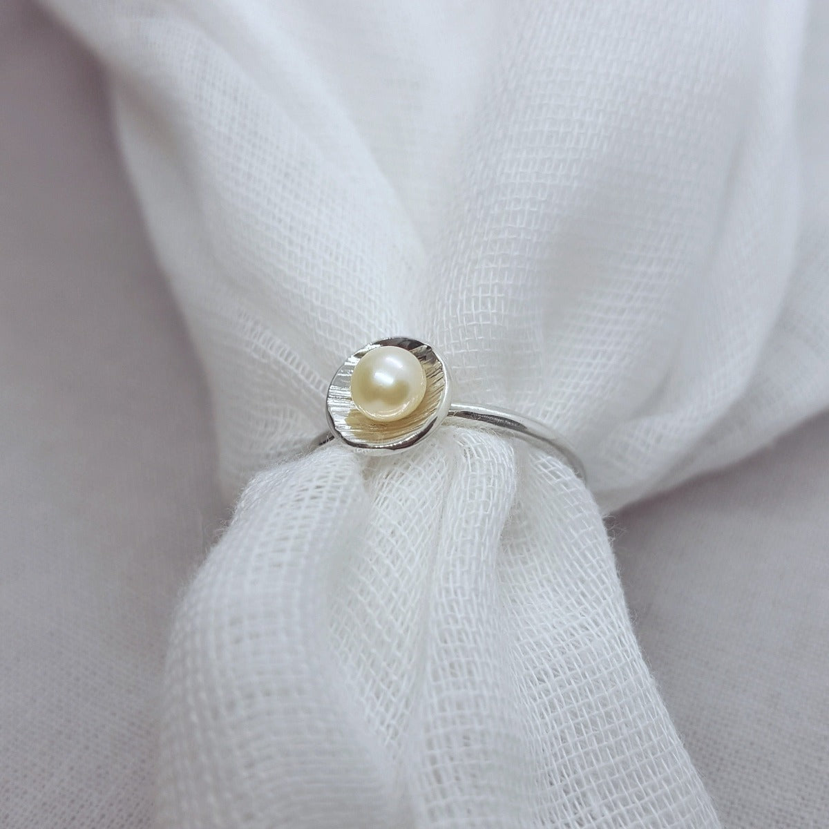 white freshwater button pearl set in a textured silver cup, handmade jewellery in Kent