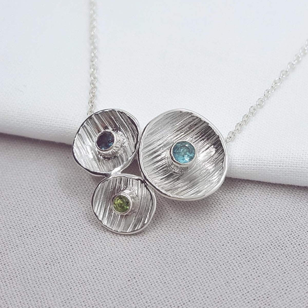 blue and green gemstones set in textured silver cups necklace