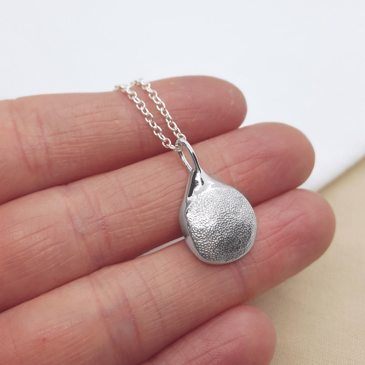 handmade dog paw print captured on a solid sterling silver pendant, hanging on a silver trace chain