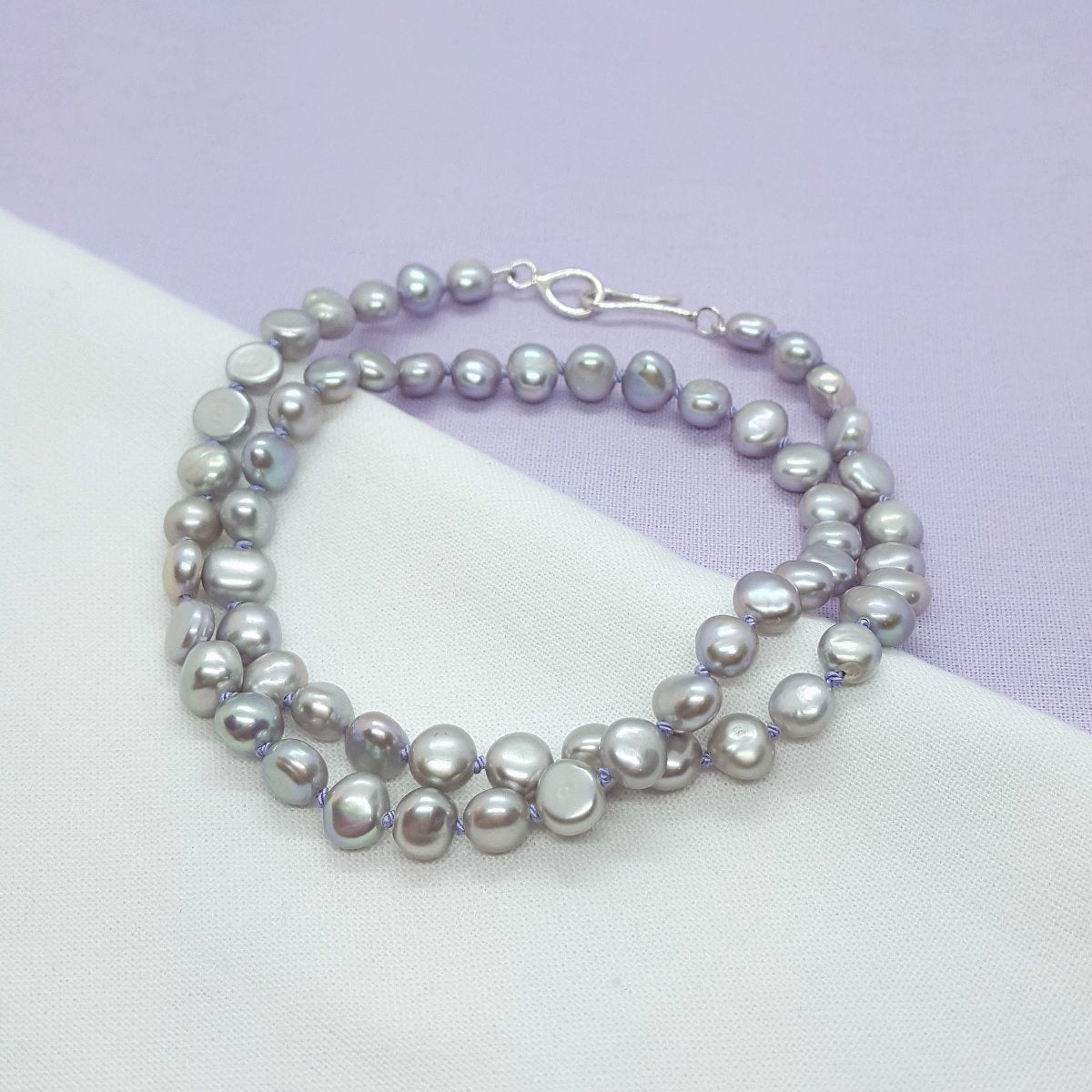 grey freshwater pearl necklace hand knotted on lilac silk thread and finished with a handmade silver clasp