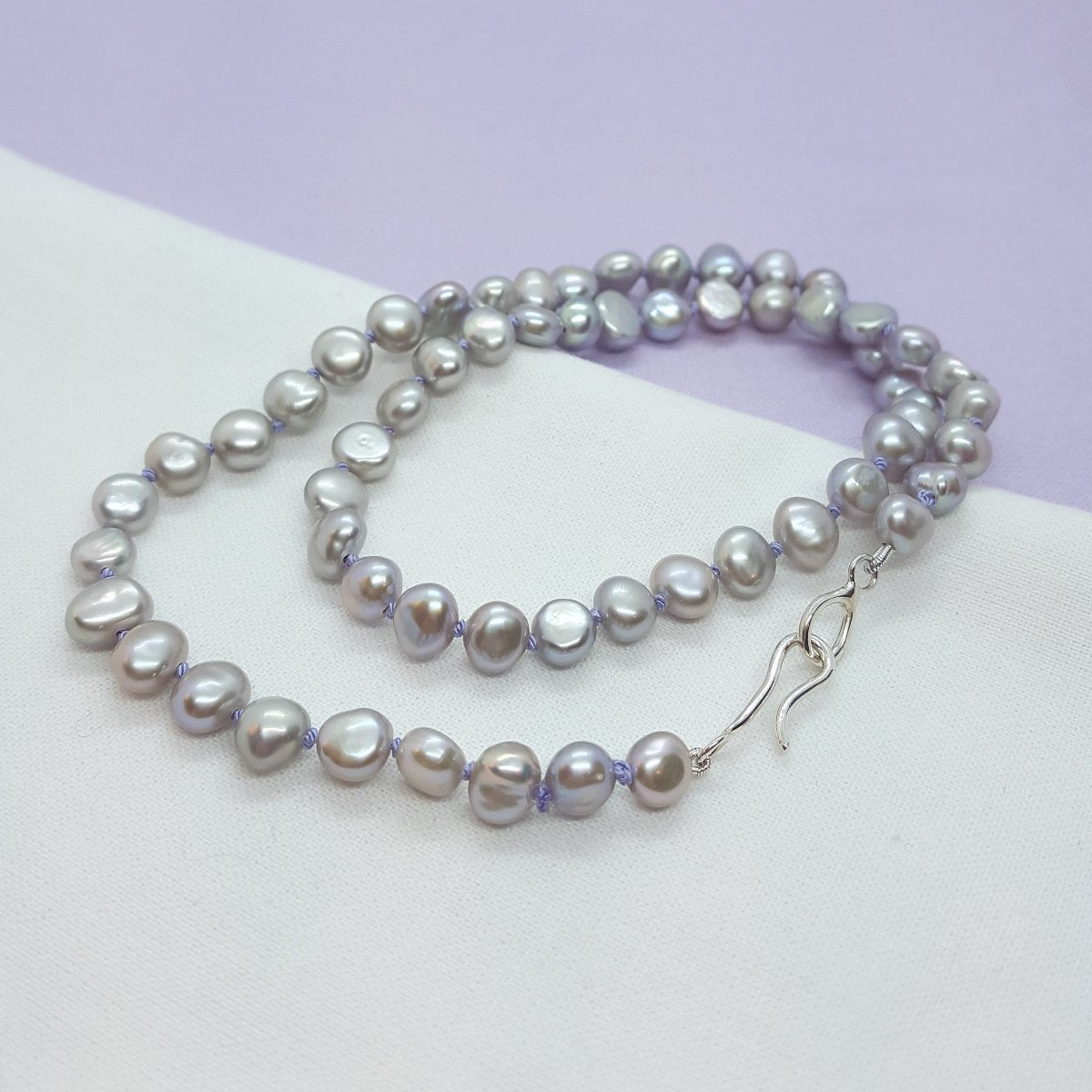 grey freshwater pearl necklace hand knotted on lilac silk thread and finished with a handmade silver clasp