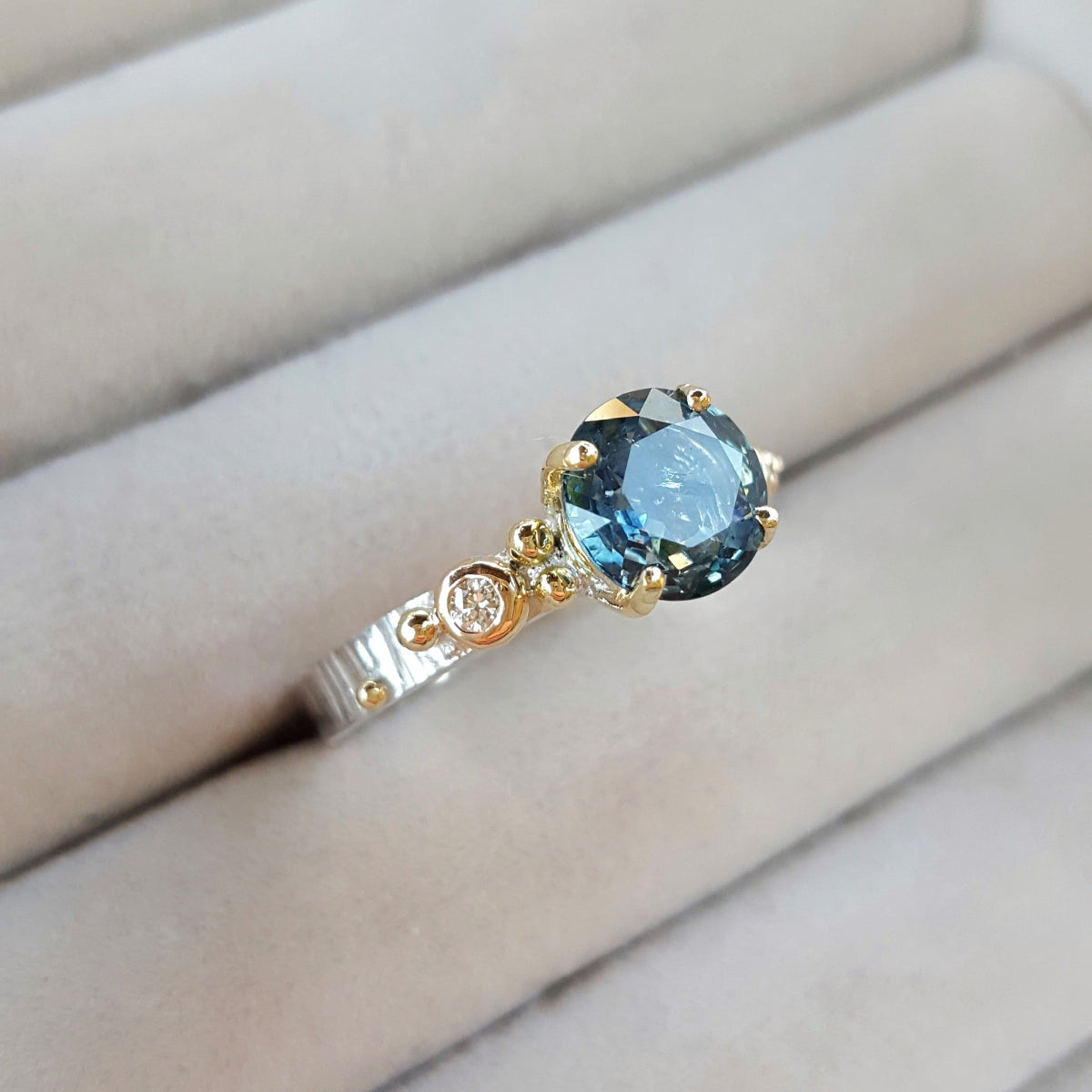 Ring with a blue gemstone and gold accents on a neutral background