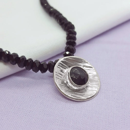 rose cut black tourmaline, set in a large textured silver disc and hung from a strand of black tourmaline faceted beads. Handmade in Kent