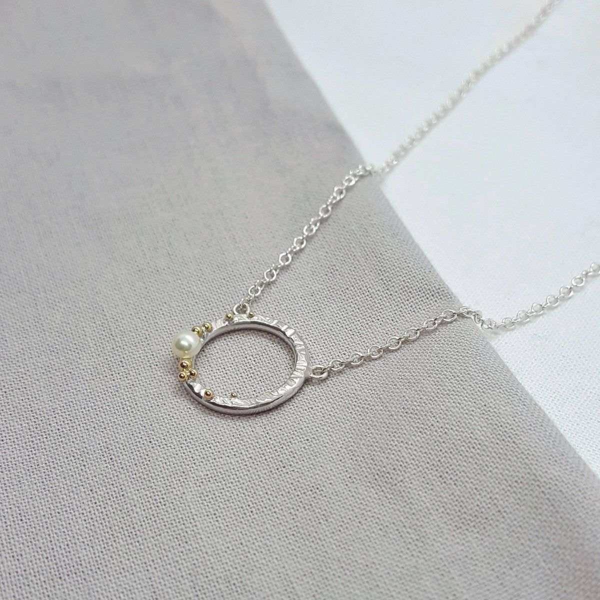 silver and 9ct yellow gold circle necklace set with a white pearl.