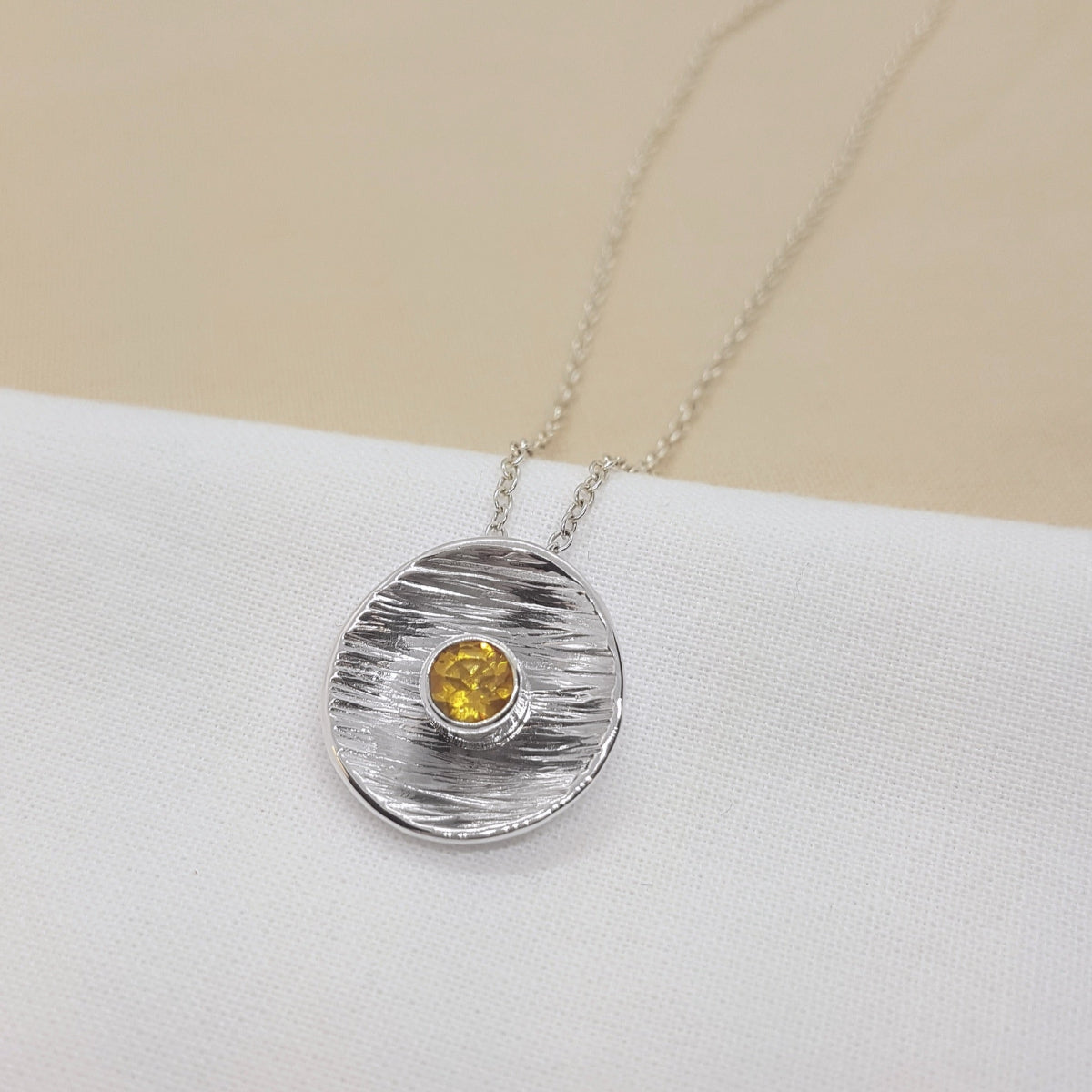 round textured disc set with a faceted citrine gemstone