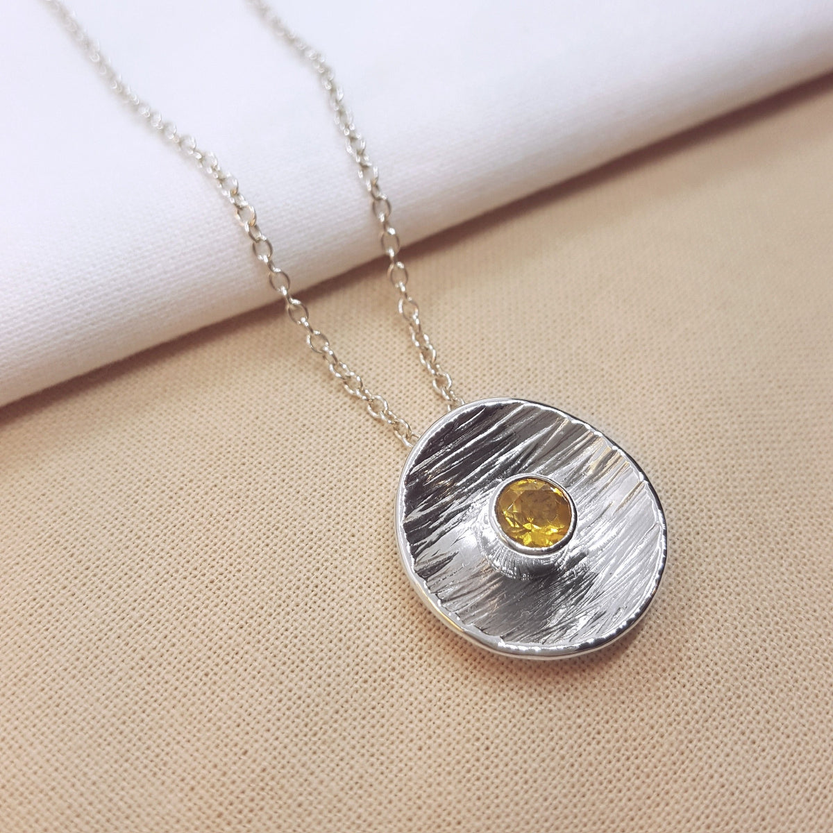 round textured disc set with a faceted citrine gemstone