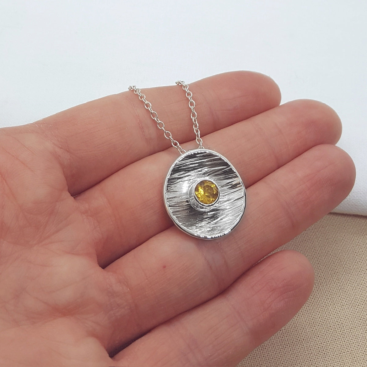 round textured disc set with a faceted citrine gemstone