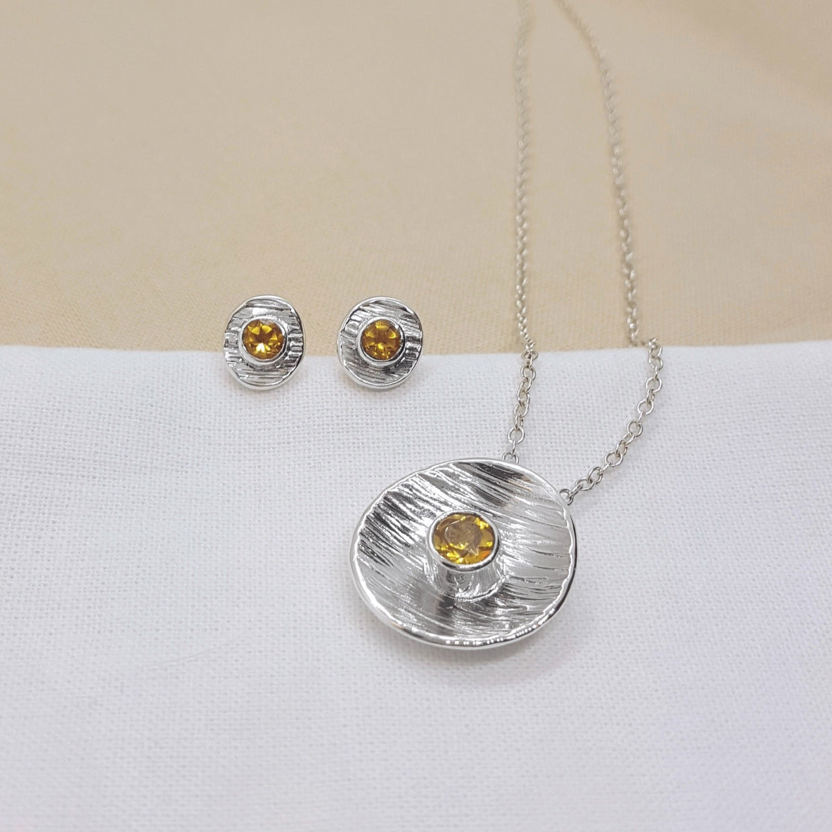 round textured disc set with a faceted citrine gemstone