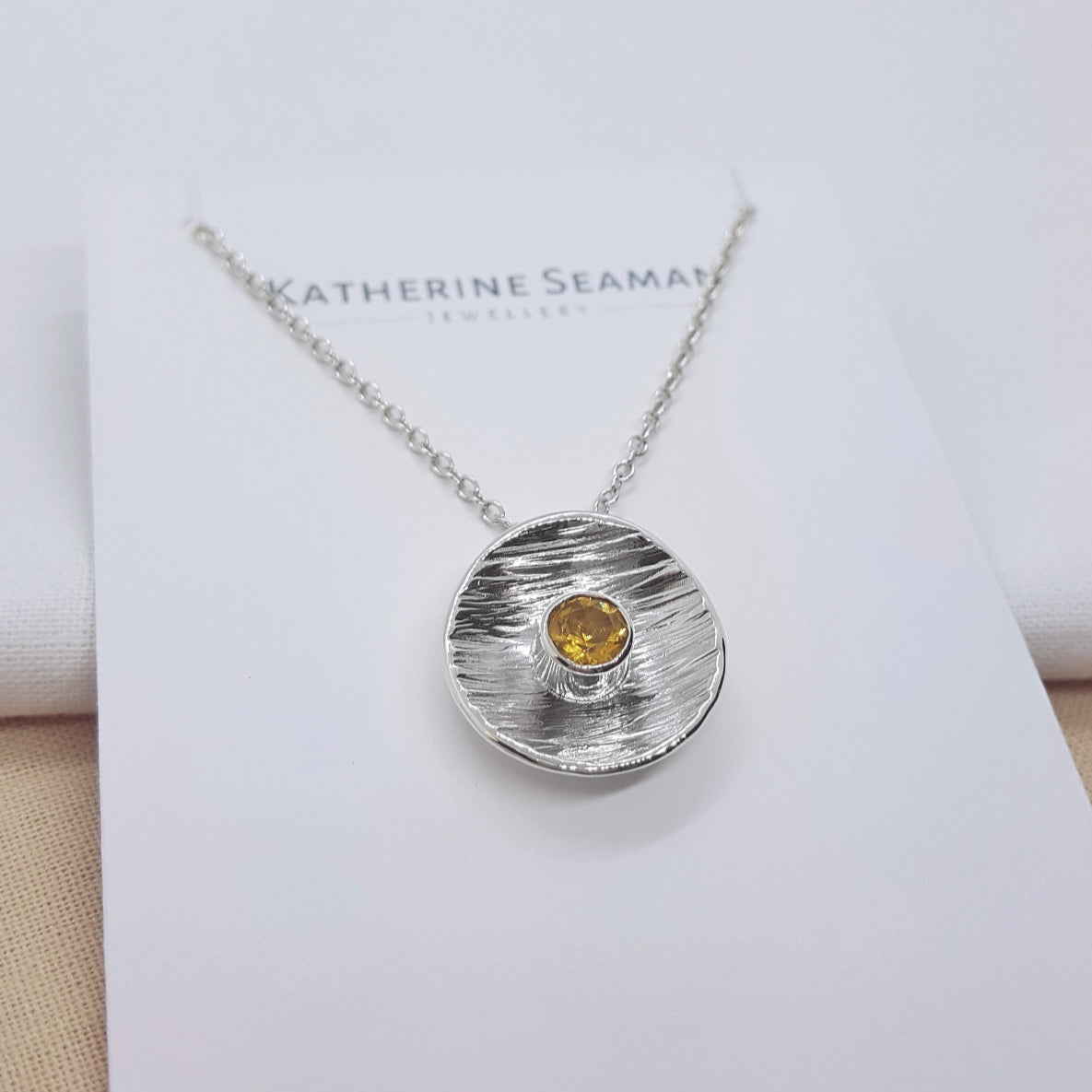 round textured disc set with a faceted citrine gemstone