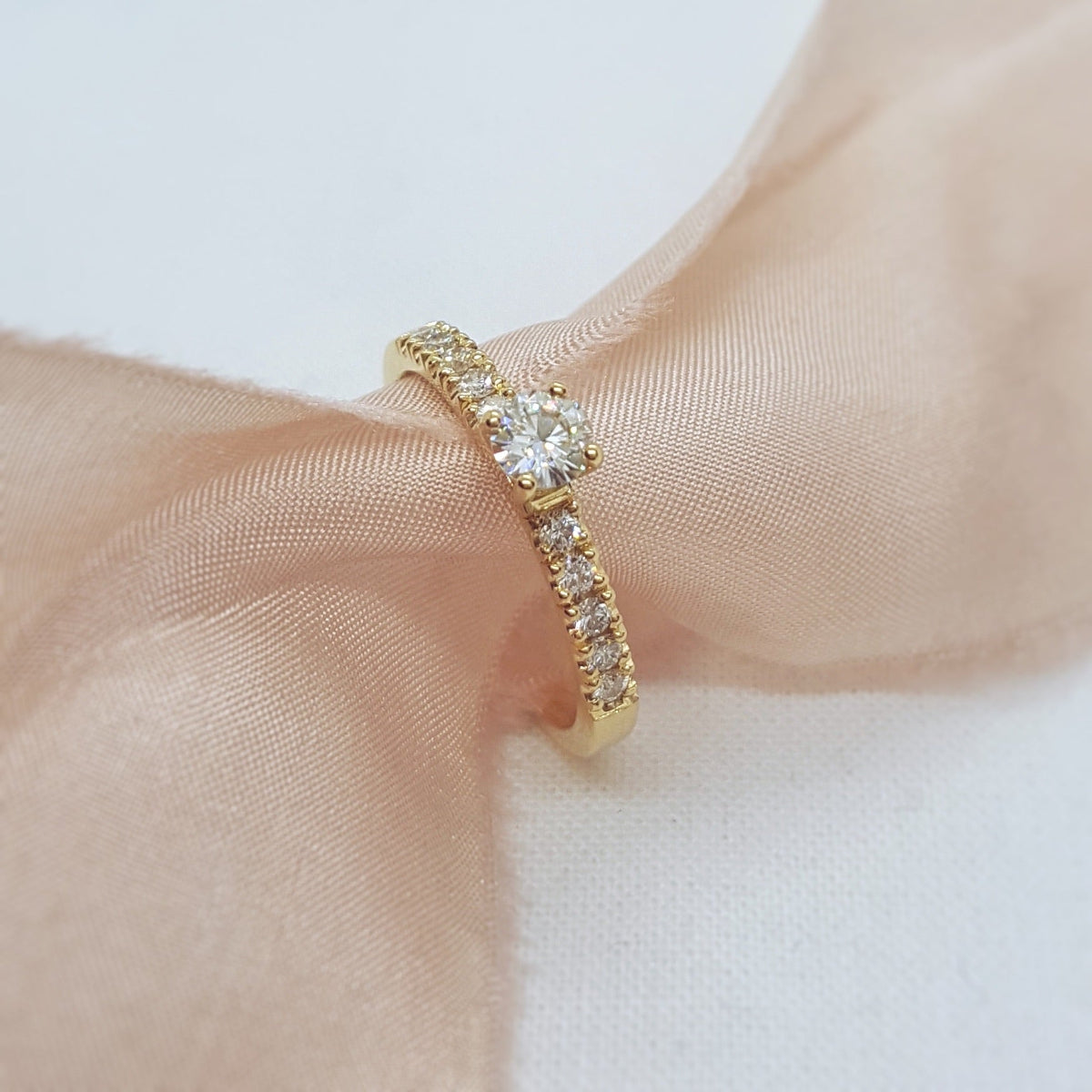 Gold ring with a diamond on a soft fabric background