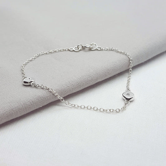 Silver bracelet with heart-shaped charms on a light gray fabric background