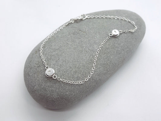 Silver bracelet on a gray stone with a white background