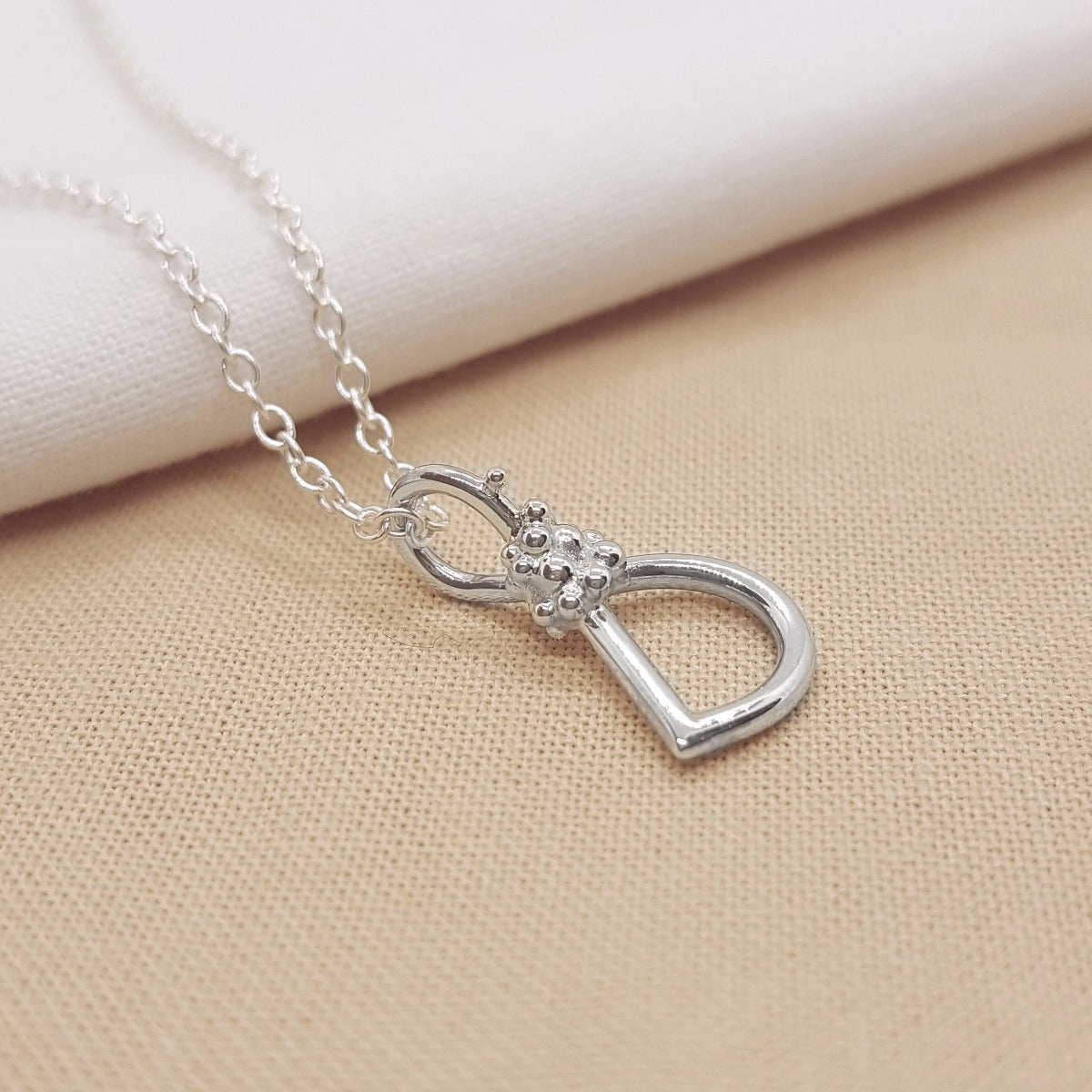 silver handmade initial pendant with granulation detail, hanging on a silver trace chain