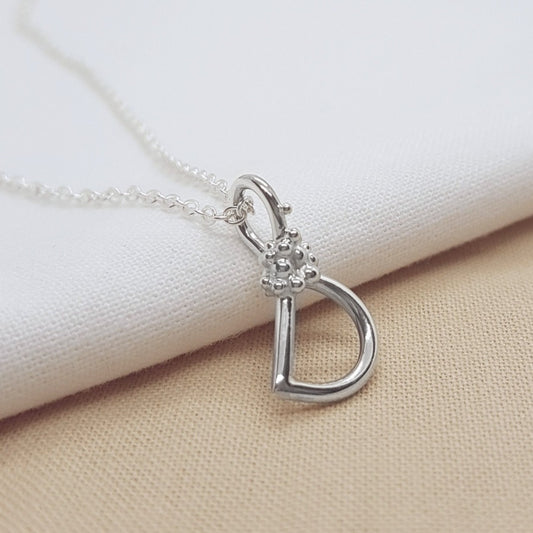 silver handmade initial pendant with granulation detail, hanging on a silver trace chain