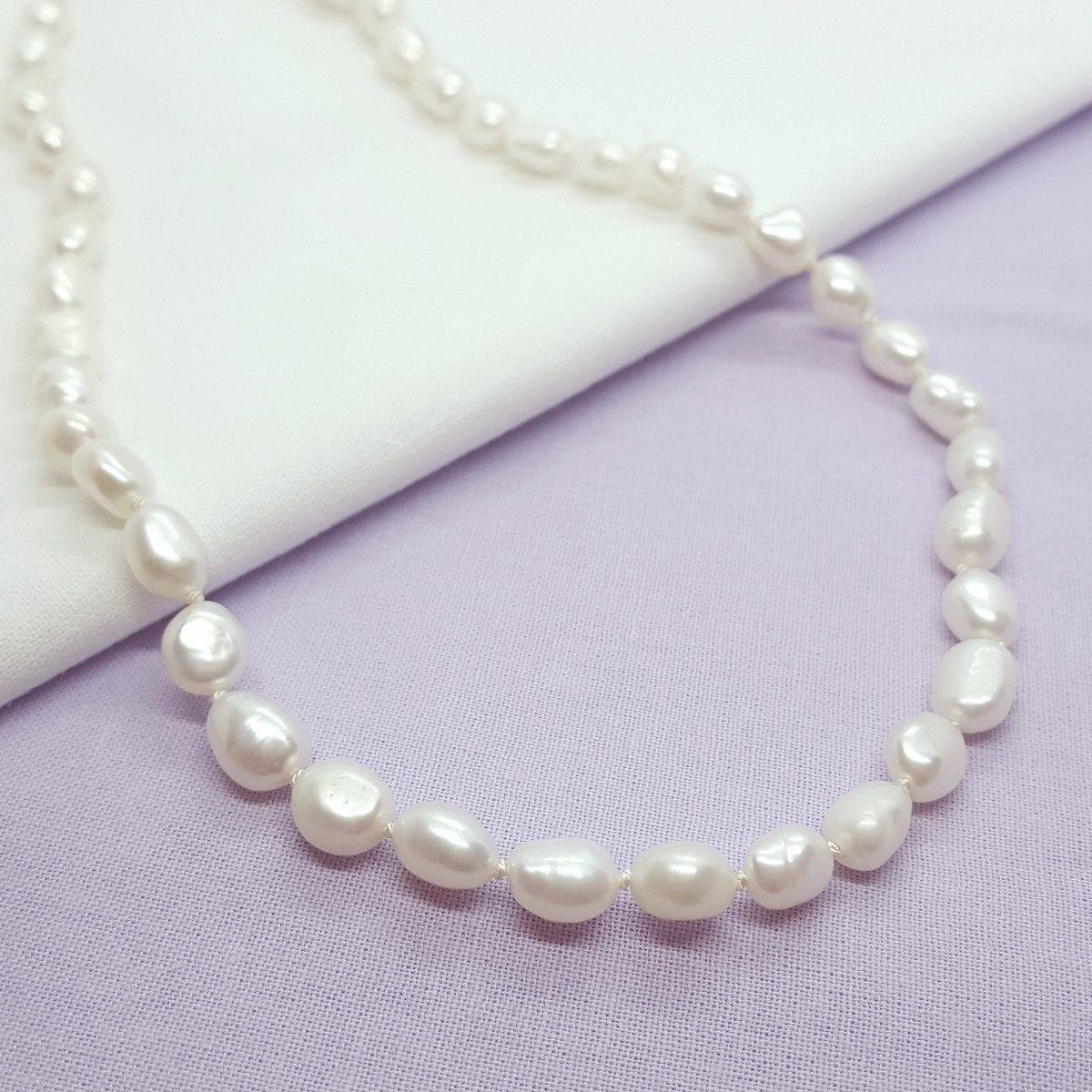 white baroque freshwater pearls hand knotted on white silk thread and finished with a handmade silver clasp and extension chain.