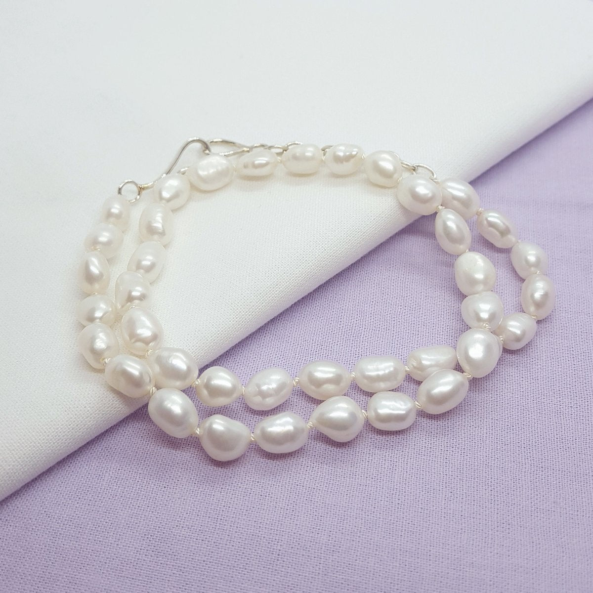 white baroque freshwater pearls hand knotted on white silk thread and finished with a handmade silver clasp and extension chain.