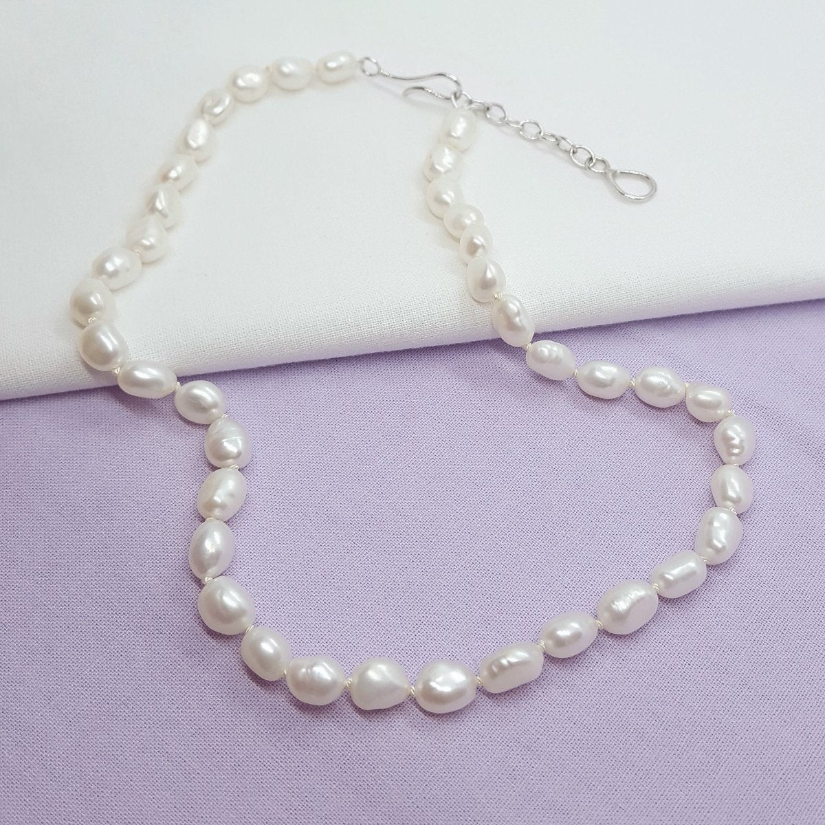 white baroque freshwater pearls hand knotted on white silk thread and finished with a handmade silver clasp and extension chain.