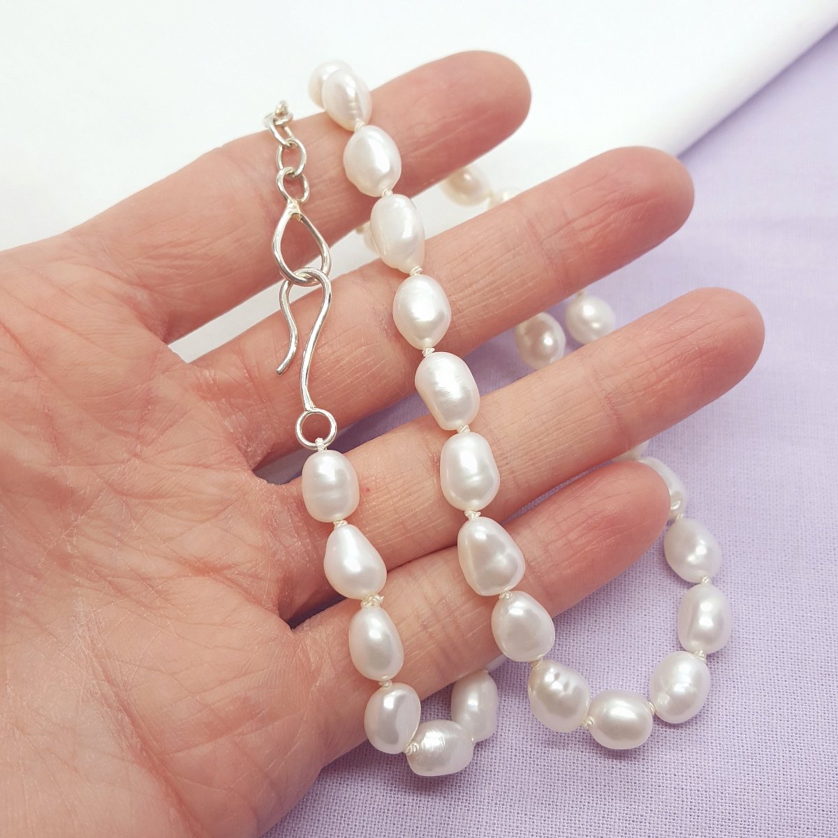 white baroque freshwater pearls hand knotted on white silk thread and finished with a handmade silver clasp and extension chain.