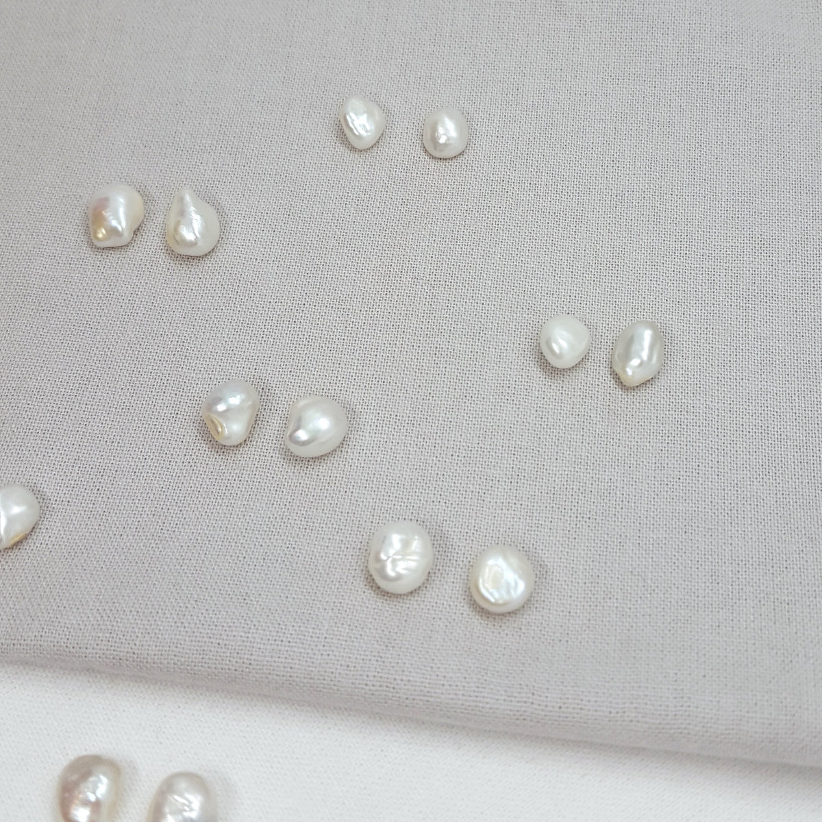 Pearls scattered on a light gray fabric background