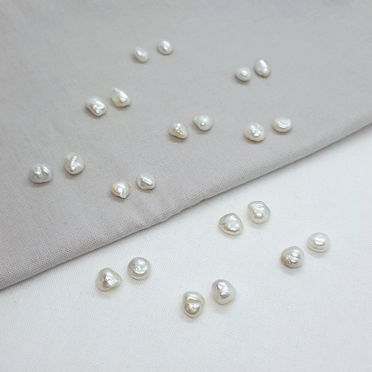 Pearls scattered on a gray and white fabric background