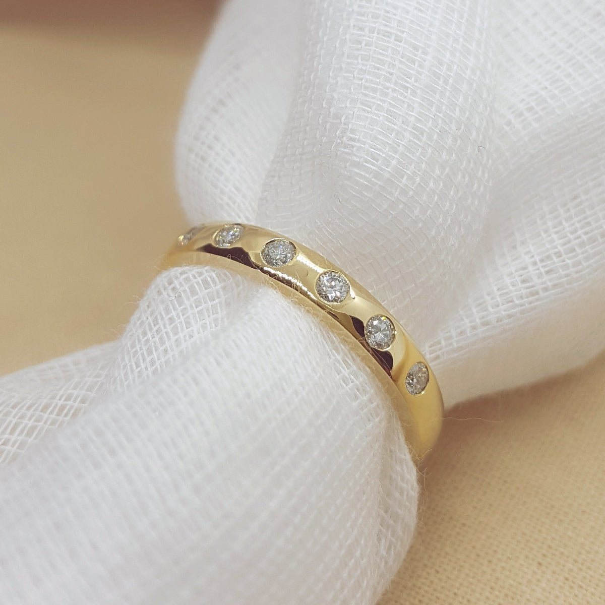 Gold ring with embedded diamonds on a white fabric background